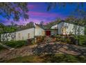 Twilight view of a modern home with colorful landscaping and a brick driveway at 2947 Cedar Trce, Tarpon Springs, FL 34688