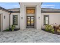 Home with a tile driveway, trimmed grass, and double door entrance at 33228 Kateland Dr, Wesley Chapel, FL 33545