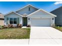 Charming single-Gathering home featuring manicured lawn, two-car garage, light gray exterior and pleasant landscaping at 5166 Plumeria Dr, Wimauma, FL 33598