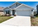 Charming single-Gathering home featuring manicured lawn, two-car garage, light gray exterior and pleasant landscaping at 5166 Plumeria Dr, Wimauma, FL 33598