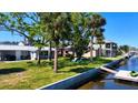 Backyard view featuring a dock, mature trees, lush green grass and a glimpse of the well maintained home at 5425 Bluepoint Dr, Port Richey, FL 34668