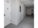 Neutral hallway with a gray floor, white walls and window, with a view of the entrance door at 7 Elgin Pl # 510, Dunedin, FL 34698