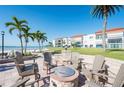 Community brick fire pit surrounded by chairs, palm trees, and beachfront condominium buildings at 825 S Gulfview Blvd # 202, Clearwater Beach, FL 33767