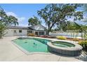 Backyard pool and hot tub feature a screened enclosure and tropical landscaping at 8302 W Pocahontas Ave, Tampa, FL 33615