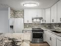 Stylish kitchen with white cabinets, granite countertops, stainless steel appliances, and chic mosaic backsplash at 9481 Highland Oak Dr Dr # 508, Tampa, FL 33647