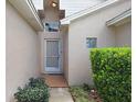 Front entrance featuring a glass-paneled storm door, beige stucco, and lush landscaping at 10509 Deepbrook Dr, Riverview, FL 33569
