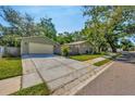 Home exterior featuring a detached garage and a spacious driveway, complemented by lush green lawn and mature trees at 1155 Withlacoochee St, Safety Harbor, FL 34695