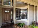 Home entrance showcasing a wood door, white framed windows, and manicured landscaping at 14678 Village Glen Cir, Tampa, FL 33618