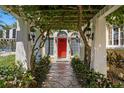 Charming front entrance with a stone pathway, climbing vines, a bright red door, and decorative lanterns at 321 Brightwaters Ne Blvd, St Petersburg, FL 33704