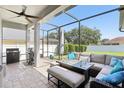 Inviting screened patio with comfortable seating, outdoor kitchen and ceiling fan at 5119 Whispering Leaf Trail, Valrico, FL 33596