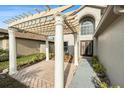 Charming home entrance featuring a pergola with white columns, brick pavers, and a decorative front door at 5410 Treig Ln, Wesley Chapel, FL 33545