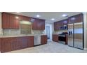 Spacious kitchen featuring rich wood cabinets, stainless steel appliances, granite countertops, and tile flooring at 5449 Manatee Point Dr, New Port Richey, FL 34652