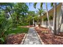 Home featuring a pathway through a landscaped yard and a charming, covered porch at 710 N River Rd, Venice, FL 34293