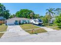 Cozy home with a well-manicured lawn and an RV parked in the driveway at 9086 Enchantment Dr, Largo, FL 33773