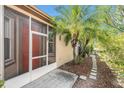 Screened-in front porch with a red door, complemented by lush landscaping and a stone pathway at 7519 Berna Ln, Land O Lakes, FL 34637