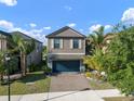 Beautiful two-story home featuring a paved driveway and lush, tropical landscaping at 10005 Sage Creek Dr, Ruskin, FL 33573
