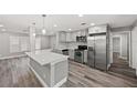 Modern kitchen with stainless steel appliances, gray cabinets, quartz countertop island, and wood-look flooring at 1002 Fruitland Ave, Bradenton, FL 34207