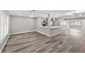 Open-concept living room featuring wood-look floors, gray walls, stylish lighting, and a kitchen bar area at 1002 Fruitland Ave, Bradenton, FL 34207