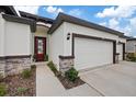 Well-maintained home featuring a three-car garage, stone veneer accents, and a red front door at 1043 Davis Heather Cir, Seffner, FL 33584
