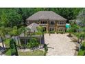Aerial view of an elegant two-story home with a tile roof, large brick driveway, and lush landscaping at 14809 Ninebark Ct, Land O Lakes, FL 34638
