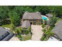 Aerial view of a large home with pool, lush landscaping, brick paver driveway and tile roof at 14809 Ninebark Ct, Land O Lakes, FL 34638