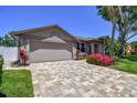 Driveway with decorative pavers leading to a two-car garage with manicured lawn at 18533 Avocet Dr, Lutz, FL 33558