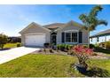 Charming single-story home with well-kept lawn and garden featuring a young palm and bright flowers at 25317 E Lenox Cir, Punta Gorda, FL 33950