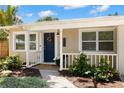 Charming home featuring a vibrant blue door and covered front porch, with lush landscaping at 4519 S Grady Ave, Tampa, FL 33611