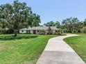 Inviting single-story home showcasing a long driveway leading up to the entrance, framed by lush greenery at 6310 95Th E St, Bradenton, FL 34202