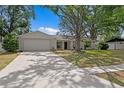 Inviting single-story home with a spacious driveway and a lush, green lawn partially shaded by mature trees at 6712 Jennifer Dr, Temple Terrace, FL 33617