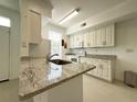 Bright kitchen featuring granite countertops, white cabinetry, and stainless-steel appliances at 9650 Lake Chase Island Way # 9650, Tampa, FL 33626