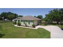 Attractive house with a green lawn, mature shrubs, and a paved driveway leading to an attached garage at 9876 Pangola Loop, Land O Lakes, FL 34639