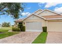 Well-kept single-story home featuring a brick driveway, lush landscaping, and a 2-car garage in a sunny neighborhood at 2309 New Orchard Ct, Sun City Center, FL 33573