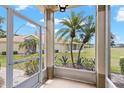 Enclosed porch with decorative glass door with a view of a lush, tropical landscape with palm trees at 2309 New Orchard Ct, Sun City Center, FL 33573