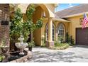 Close-up of the home's entryway with brick accents, arched windows, and lush greenery at 2513 Regal River Rd, Valrico, FL 33596