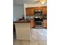Well-lit kitchen with wooden cabinets, stainless steel appliances, and a tiled floor at 2961 Flint N Dr, Clearwater, FL 33759