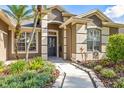 Elegant home entrance featuring a dark-colored front door, beautiful landscaping, and charming walkway at 3119 Bent Creek Dr, Valrico, FL 33596