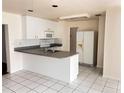 Kitchen with white cabinets, white appliances, and tiled flooring at 3655 Dellefield St, New Port Richey, FL 34655