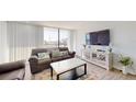 Cozy living room featuring a comfortable sofa, entertainment center, and a sliding glass door to a balcony at 400 Island Way # 210, Clearwater Beach, FL 33767