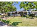 Inviting single-story home features a well-manicured lawn and lush trees in a quaint neighborhood setting at 401 Patica Ne Rd, St Petersburg, FL 33702