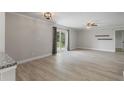 Spacious living room featuring wood-look tile flooring, neutral walls, and sliding glass doors leading to the backyard at 4148 102Nd N Pl, Clearwater, FL 33762