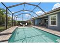 Sparkling screened-in pool with brick surround, lounge chairs, and sunny sky views offer a relaxing outdoor experience at 5609 Silver Sun Dr, Apollo Beach, FL 33572