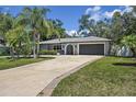Well-maintained single-story home with a long driveway, a two-car garage, and mature landscaping at 6821 Date Palm S Ave, St Petersburg, FL 33707