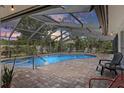 Screened-in pool area with a hot tub and various lounge chairs, surrounded by brick pavers and lush landscaping at 6821 Date Palm S Ave, St Petersburg, FL 33707