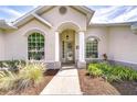 A charming front porch with white columns and arched windows, surrounded by landscaped flower beds at 7824 Primula Ln, New Port Richey, FL 34654