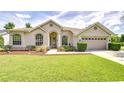 Attractive front yard with green grass, a beige-colored house, and well-trimmed bushes at 7824 Primula Ln, New Port Richey, FL 34654