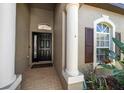 Inviting entryway with white columns, a black front door with glass, and fresh landscaping at 8103 Tar Hollow Dr, Gibsonton, FL 33534