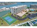 Exterior view of the waterfront condominium complex with tennis court, boat slips, and swimming pool at 1 Key Capri # 211W, Treasure Island, FL 33706