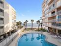 Beautiful pool view with swaying palm trees, blue skies, and ocean backdrop at 16400 Gulf Blvd # 505, North Redington Beach, FL 33708