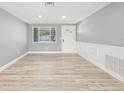 Inviting living room featuring wainscoting, modern flooring, and a view of the front yard at 2616 Ohio Pl, Holiday, FL 34691